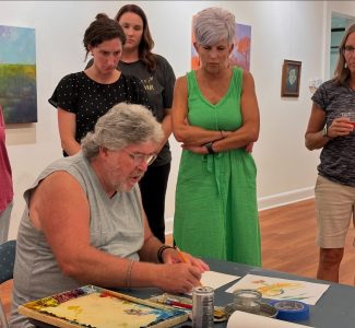 Students watch artist Kenny King demonstrate a sketch.