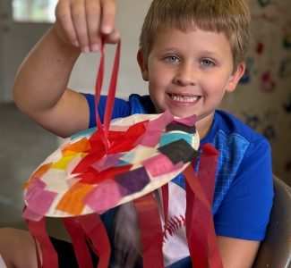 A summer camper shows off his multi-colored plated jelly fish creation.